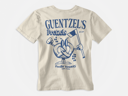 Back of shirt, cream colored, blue pretzel holding a hockey stick, Lettering across the top says Guentzel's Pretzels, wording on the bottom says Feelin Knotty, Tampa Bay Lightning